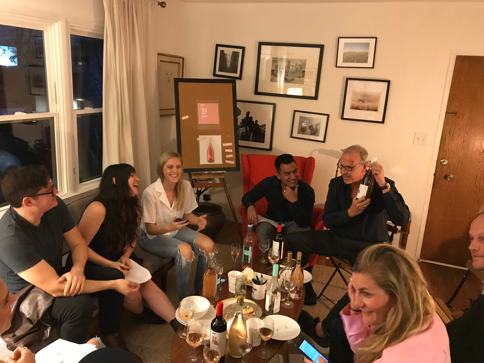 The Obvious Wines team, sitting indoors enjoying wine and laughing together